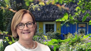 En kvinna i förgrunden och en stuga i bakgrunden.