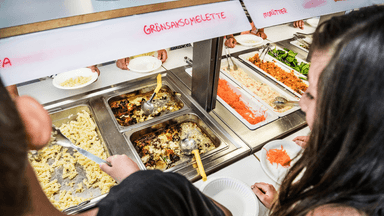 Elever som står vid skolmaten.