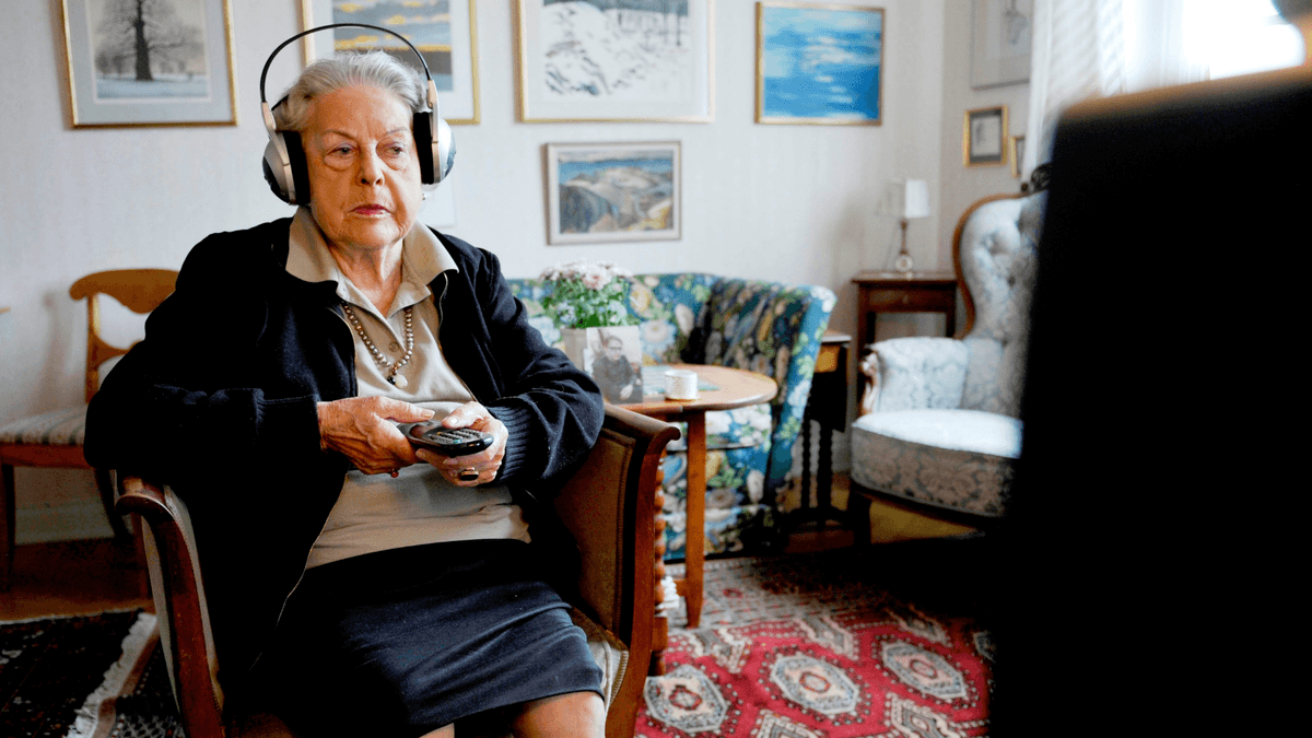 En äldre kvinna som sitter framför en tv och kollar på Youtube.
