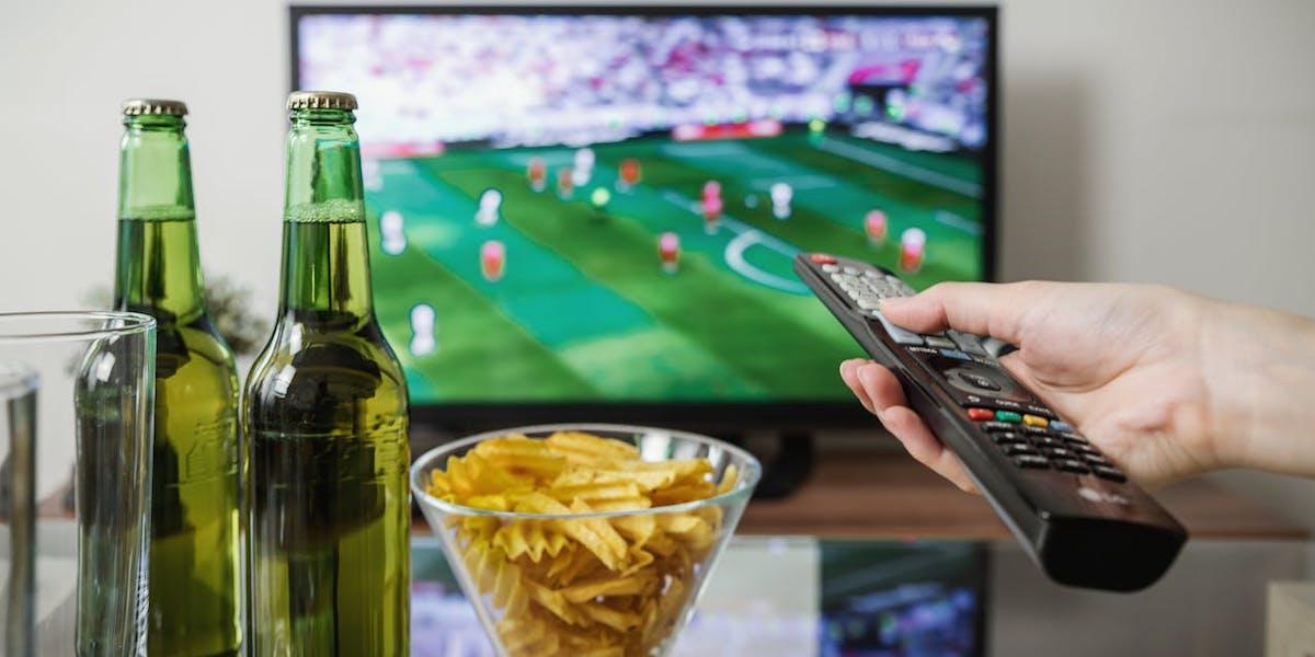 En tv med öl och chios på bordet framför. Mycket tv-tittande påverkar vår möjlighet att åldras hälsosamt, förutom att det innebär mycket stillasittande, medför det vanligtvis andra dåliga vanor, som förtäring av skräpmat