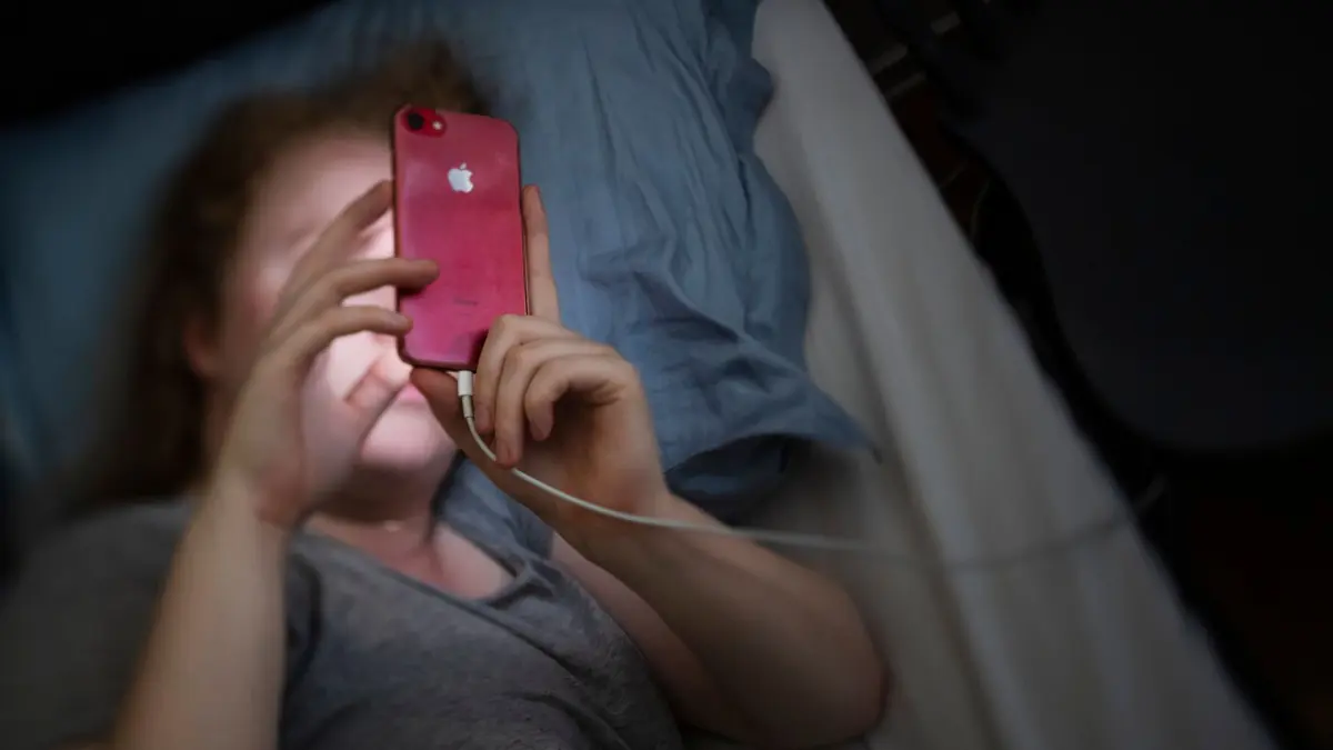 En kvinna som har problem med sömnen, i sängen med sin mobil